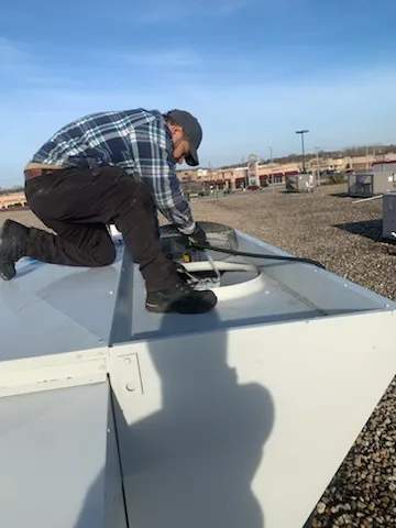 Technician servicing rooftop refrigeration equipment near Rockford, IL